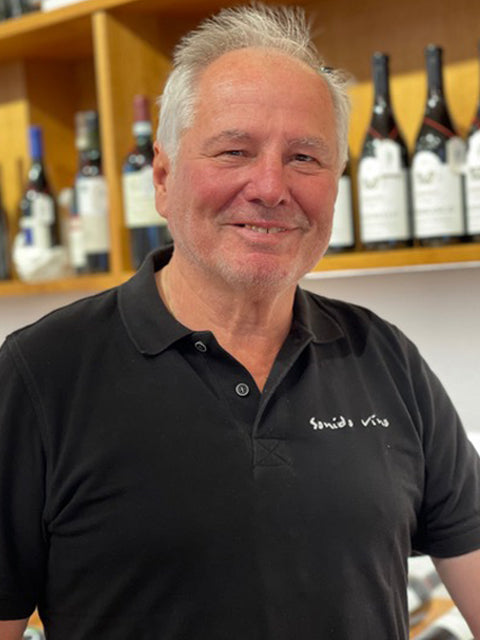 Mann vor Weinflaschen im Regal.